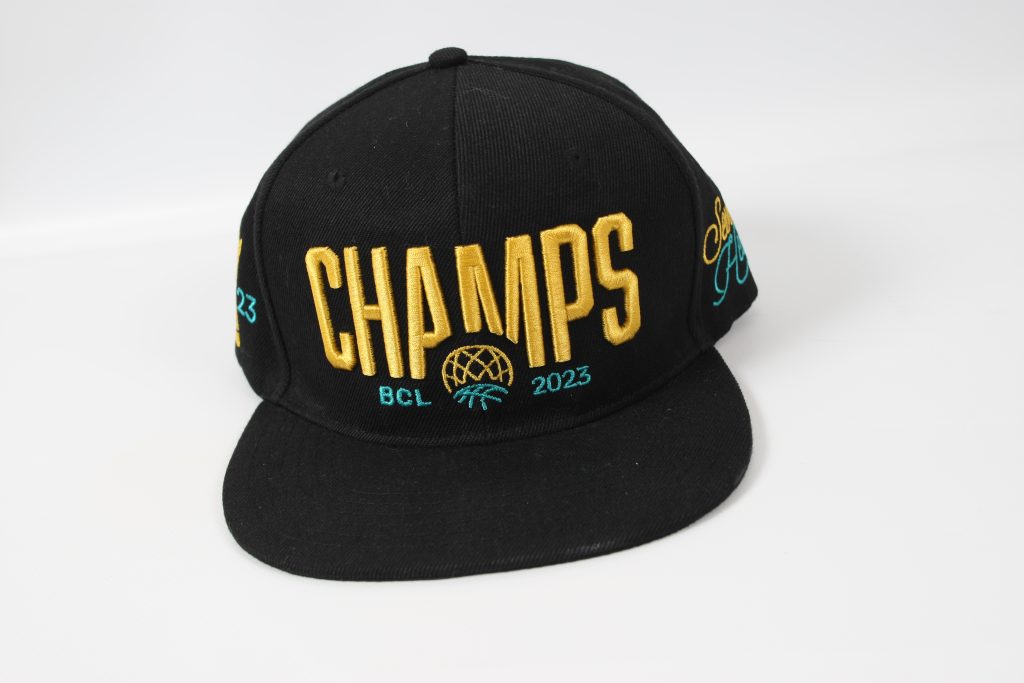 Schwarze Baseballmütze mit dem Schriftzug 'CHAMPS BCL 2023' in gold und türkis.