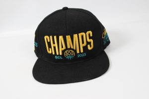 Schwarze Baseballmütze mit dem Schriftzug 'CHAMPS BCL 2023' in gold und türkis.