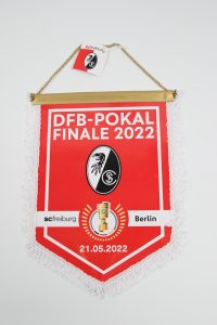 Roter Wimpel mit dem Logo von SC Freiburg und Informationen zum DFB-Pokal Finale 2022 in Berlin.
