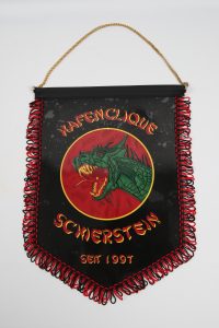 Wimpel mit einem Drachenmotiv und dem Schriftzug 'Schersten seit 1997' in roter Schrift auf schwarzem Hintergrund.