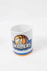 Kaffeebecher mit einem Basketball und dem Skyliners-Logo auf der Vorderseite.