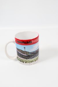 Kaffeebecher mit einem Bild des Sportclub Freiburg Stadions und dem Schriftzug 'sportclubfreiburg'.