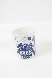 Weißer Kaffeebecher mit blauem Aufstieg Bundesliga Motiv und Spielern in Aktion.