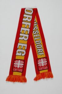 Roter Jacquard-Schal mit dem Schriftzug 'Düsseldorf' und dem Logo von Caritas.