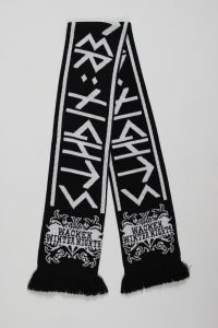 Schwarzer Jacquard-Schal mit weißen grafischen Mustern und Fransen am Ende.