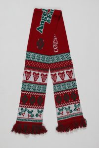 Rot-grüner Strickschal mit verschiedenen Weihnachtsmustern und Fransen am Ende.