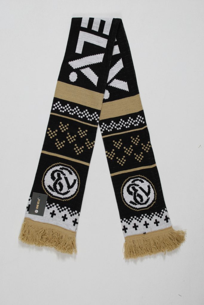 Schwarzer und goldener Jacquard-Schal mit grafischem Muster und Fransen am Ende.