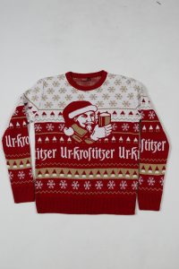 Roter Ugly Sweater mit Weihnachtsmotiv und Schneeflocken, zeigt eine Figur mit Geschenk.