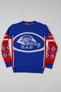 Blauer Pullover mit dem Schriftzug 'ugly-sweater.de' und roten und weißen Akzenten an den Ärmeln.