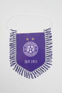 Wimpel des Fussballklubs Austria Wien mit Logo und Fransen in lila und weiß.