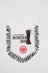 Wimpel mit der Aufschrift 'Sevillaaaaaa! IN DIESEM JAHR' und dem Logo von Eintracht Frankfurt.