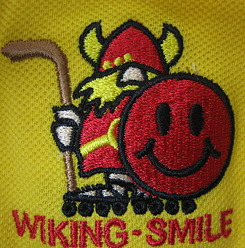 Ein gestickter Wikinger mit einem roten Smiley auf gelbem Hintergrund.
