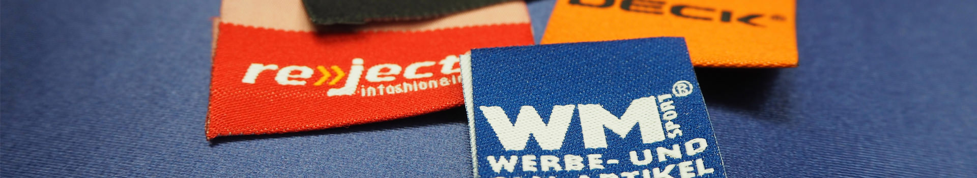 Diverse Stoffetiketten mit verschiedenen Marken und Texten, darunter WM und reject.
