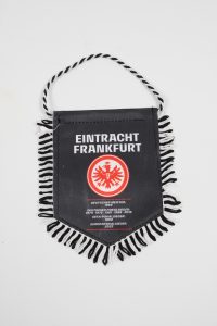 Schwarzer Wimpel mit dem Logo von Eintracht Frankfurt und Text über Meisterschaften.