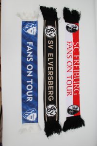 Drei Fan-Schals in den Farben von SV Elversberg und SC Freiburg mit dem Schriftzug 'FANS ON TOUR'.