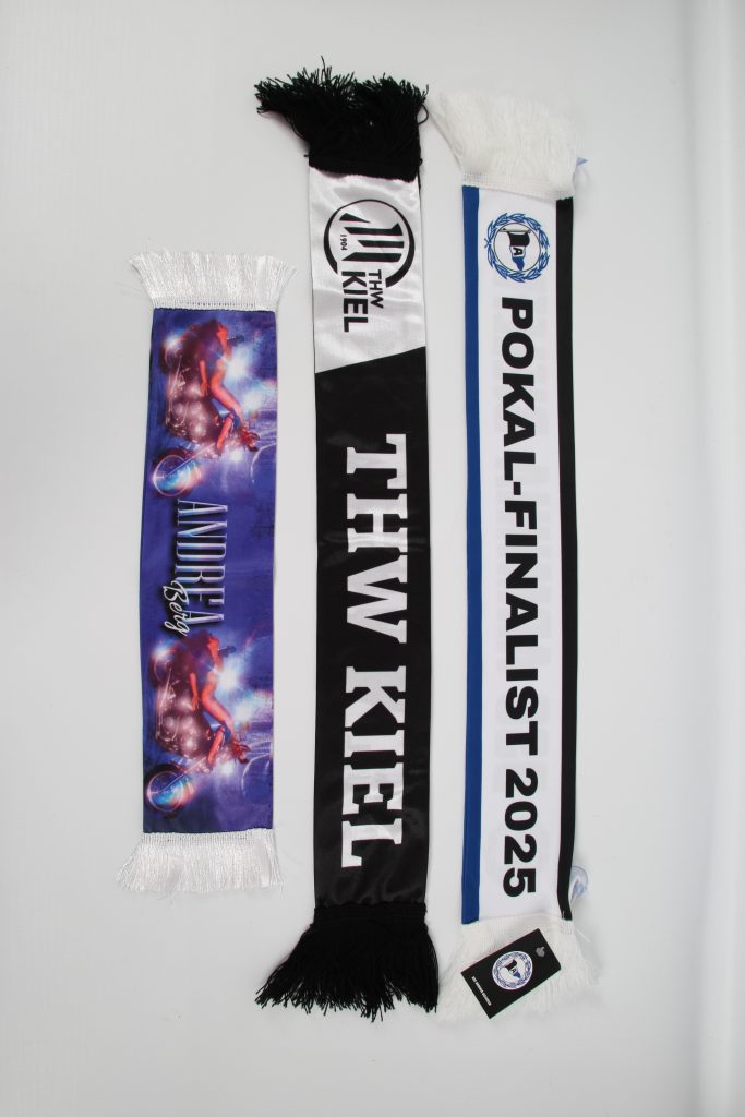 Drei Schals, darunter ein THW Kiel Schal und ein Schal für Pokal-Finalist 2025, mit Fransen an den Enden.