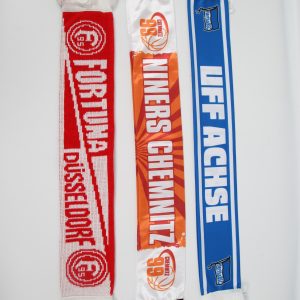 Drei Fan-Schals in den Farben Rot, Orange und Blau, jeweils mit Vereinsnamen und Wappen.