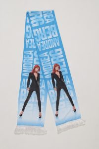 Schal mit einem Motiv von Andrea Berg in schwarzem Outfit und fransigem Ende auf blauem Hintergrund.