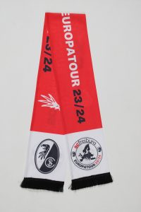 Rot-weißer Schal mit dem Logo des SC Freiburg und dem Schriftzug 'Europatour 23/24'.