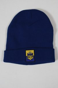 Blauer Beanie mit einem gelben Aufnäher, der ein Wappen zeigt, auf einem neutralen Hintergrund.