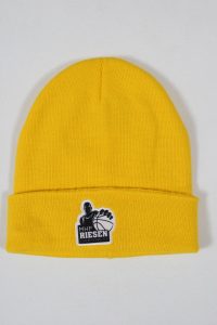 Gelbe Beanie-Mütze mit einem Aufnäher des MHP Riesen Logos.