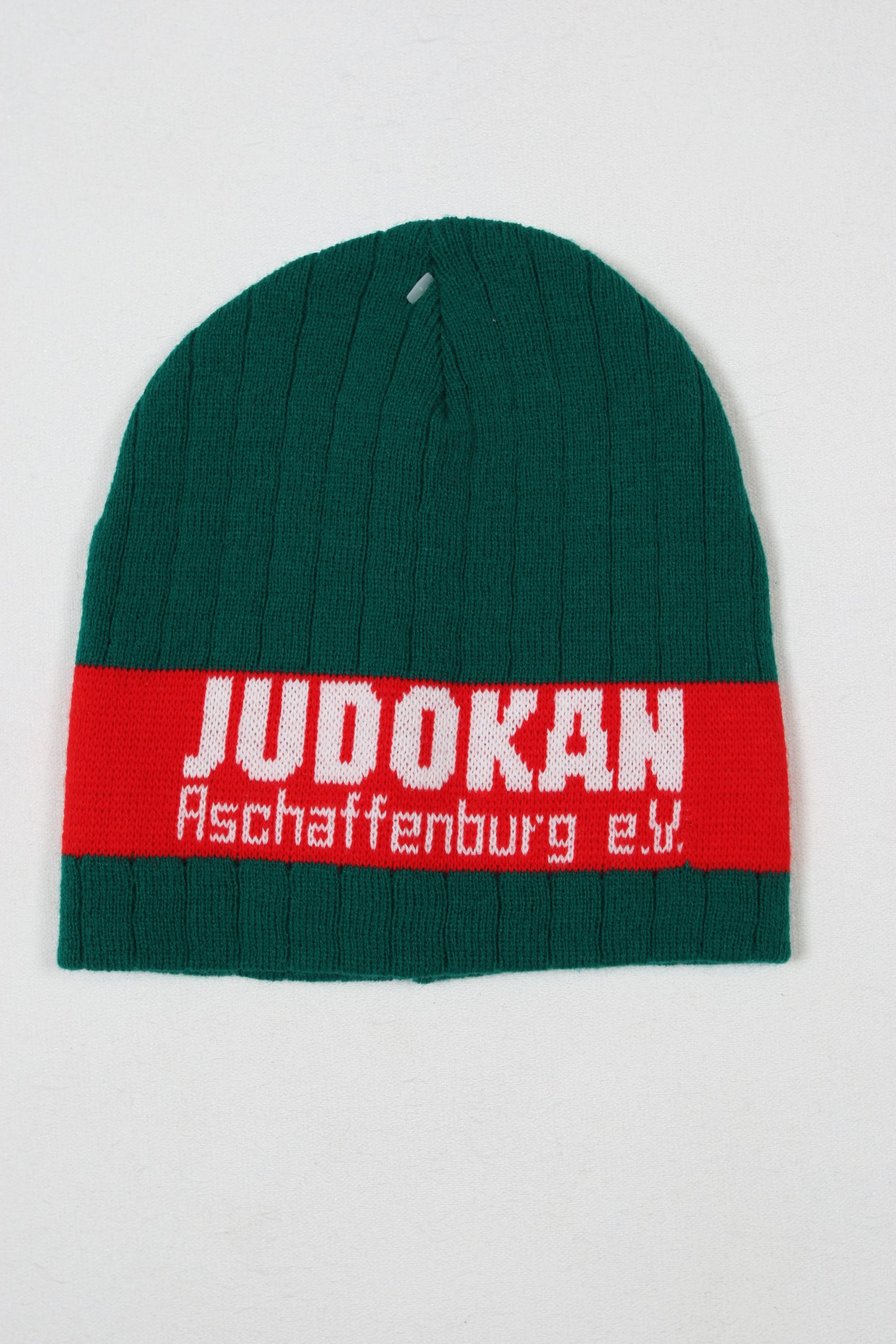 Grüne Strickmütze mit rotem Band und dem Schriftzug Judokan Aschaffenburg e.V. in Weiß.