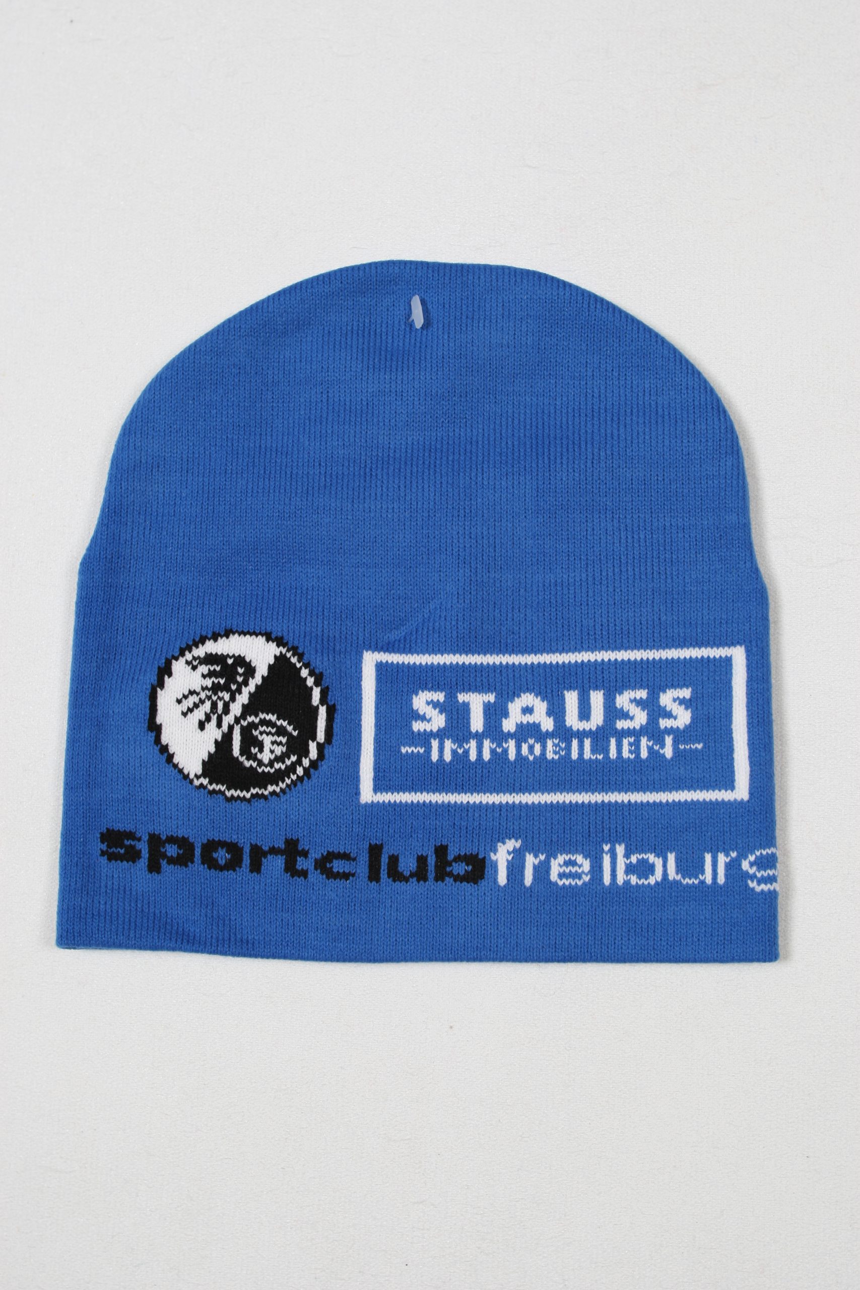 Blaue gestrickte Mütze mit dem Logo des Sportclubs Freiburg und der Aufschrift 'Strauss Immobilien'.