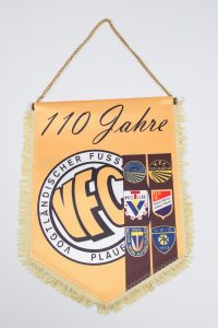 Jubiläumswimpel des VFC Plauen mit verschiedenen Vereinswappen und der Aufschrift '110 Jahre'.