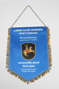 Banner des Lions Club Wurzen mit dem Wappen und dem Motto des Clubs.