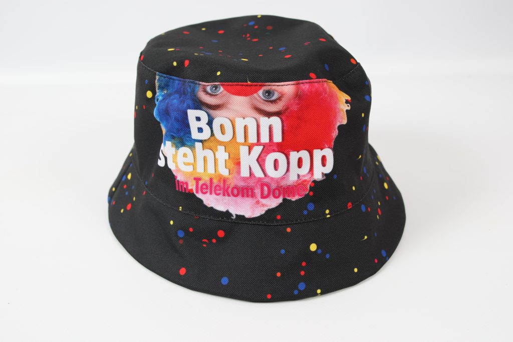 Schwarzer Fischerhut mit buntem Aufdruck, der den Text 'Bonn steht Kopf im Telekom Dome' zeigt.