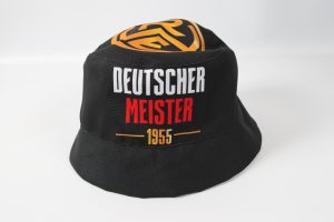 Schwarzer Fischerhut mit goldener und roter Aufschrift Deutscher Meister 1955 auf der Vorderseite.