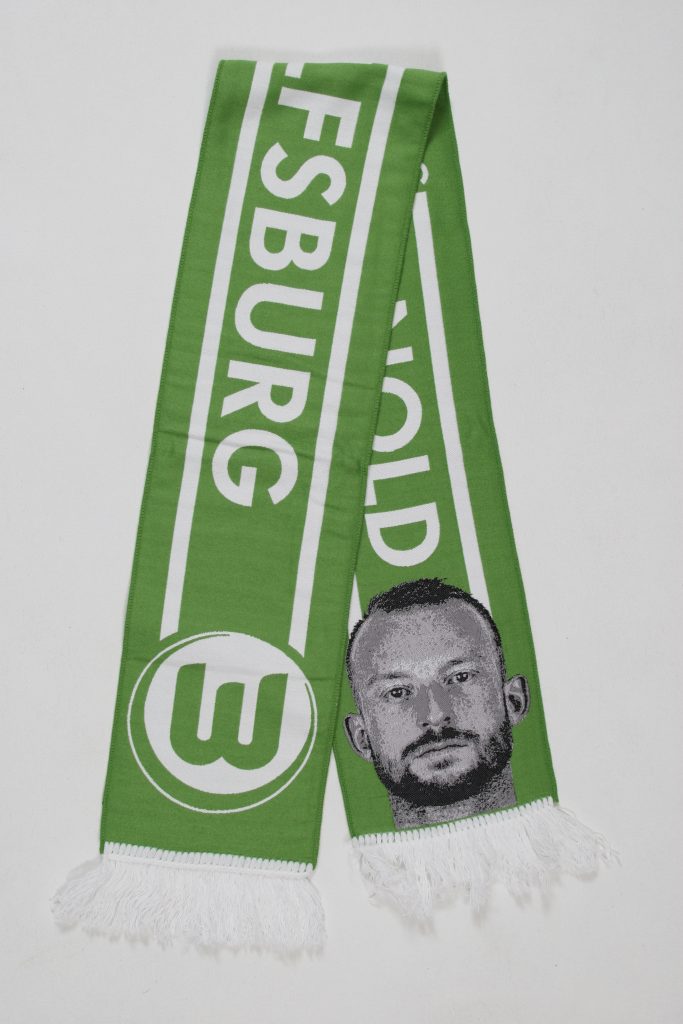Grüner Schal mit dem Schriftzug 'Wolfsburg' und einem Gesichtsdruck auf der Vorderseite.