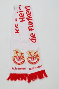 Weißer Schal mit dem Schriftzug 'Heim die Funken' und dem Wappen der Roten Funken in Rot.
