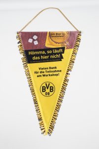 Gelber Ligawimpel mit schwarzem Text und BVB 09 Logo, dekoriert mit einer Kette.