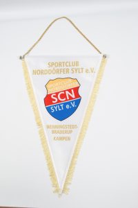 Wimpel des Sportclub Norddörfer Sylt e.V. mit goldener Schrift und Fransen.