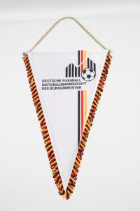 Wimpel der Deutschen Fußballnationalmannschaft mit bunten Fransen und Fußballmotiv.