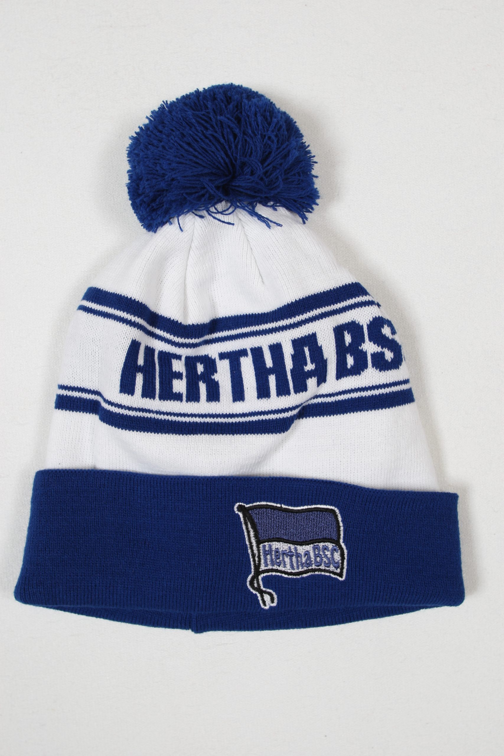 Hertha BSC Mütze in Weiß und Blau mit einem Pompon auf der Oberseite und gesticktem Logo.
