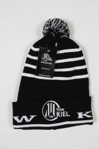 Schwarz-weiße gestrickte Mütze mit dem Logo von THW Kiel und einem Bommel auf der Oberseite.
