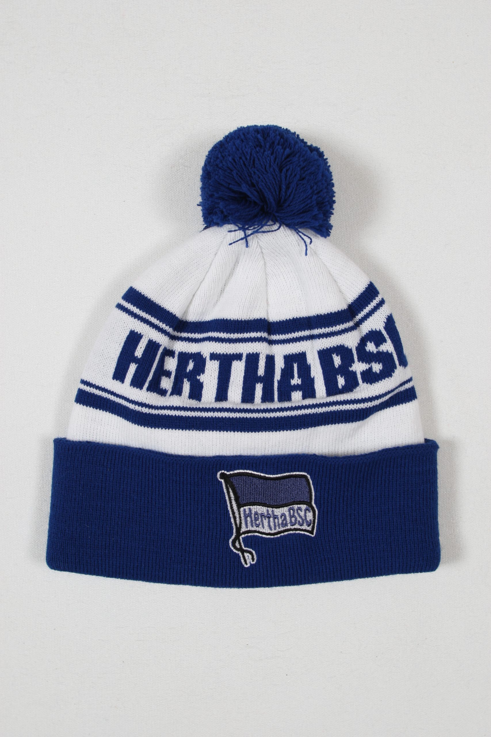 Weiße und blaue Mütze mit dem Logo von Hertha BSC und einem Bommel oben.