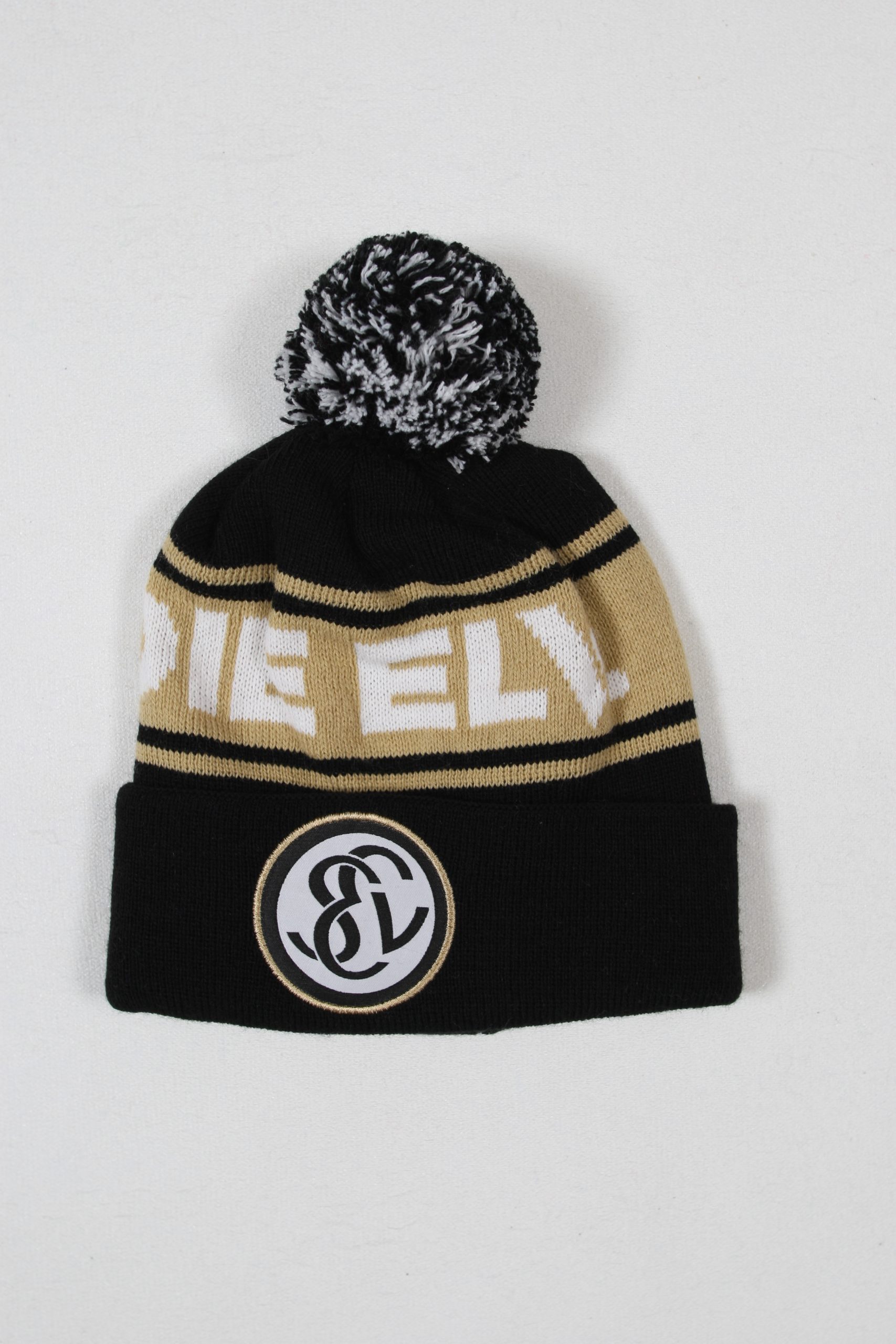 Schwarz-goldene Mütze mit einem Bommel und einem runden Logo auf der Vorderseite.
