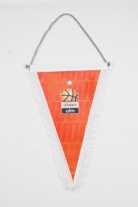 Dreieckiger Schmuckwimpel in Orange mit Basketballmotiv und Logo von ratio pharm Ulm.