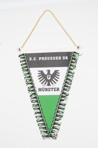 Dreieckiger Wimpel des S.C. Preussen 06 Münster mit schwarzem Adler und grünen Fransen.