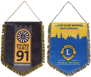 Zwei Wimpel, einer vom Round Table 91 Delmenhorst und einer vom Lions Club Wurzen, mit verschiedenen Farben und Logos.