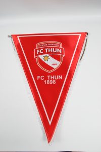Roter Wimpel mit dem Logo des FC Thun, der 1898 gegründet wurde, und einem goldenen Stern.