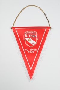 Roter Wimpel des FC Thun mit dem Vereinslogo und Fransen am unteren Rand.