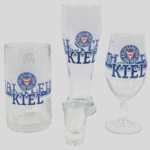 Verschiedene Gläser mit dem Kiel-Logo, darunter ein Bierkrug, ein Weizenglas, ein Schnapsglas und ein Weinglas.