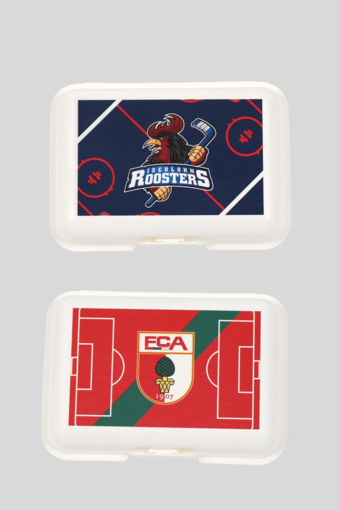 Brotdose mit dem Logo der 'Island Roosters' und einem Fußballfeld-Design.