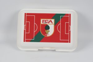 Brotdose mit rotem Design und FCA-Logo, das ein Fußballfeld darstellt.