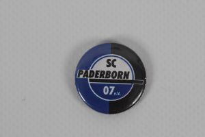 Ansteckbutton mit dem Logo von SC Paderborn 07 in Schwarz und Blau.