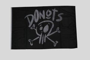 Schwarze Flagge mit einem Totenkopf und dem Schriftzug 'DONOTS' in grauer Schrift.